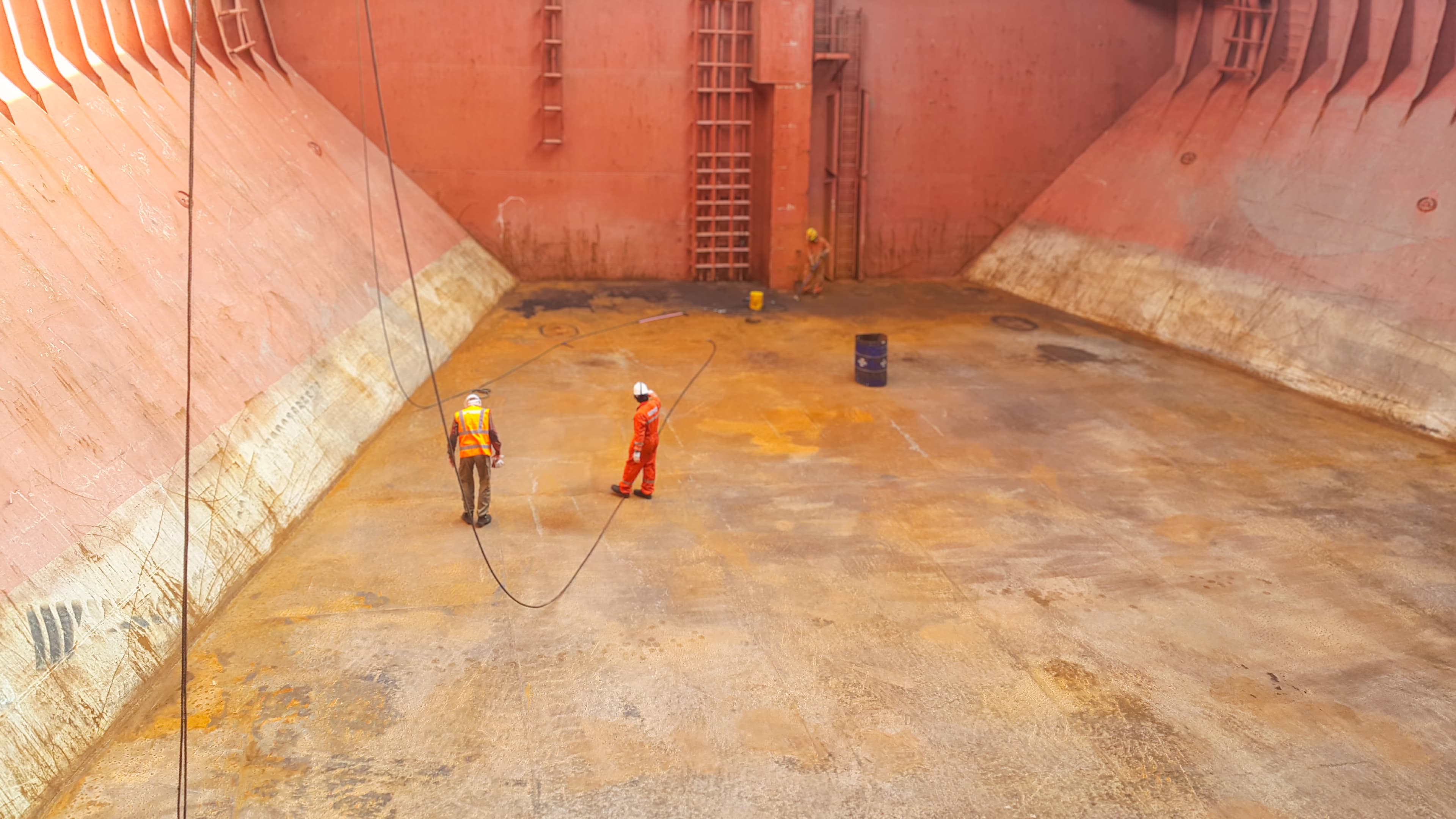 Workers inspecting a bulk carrier hold before woodchip loading.